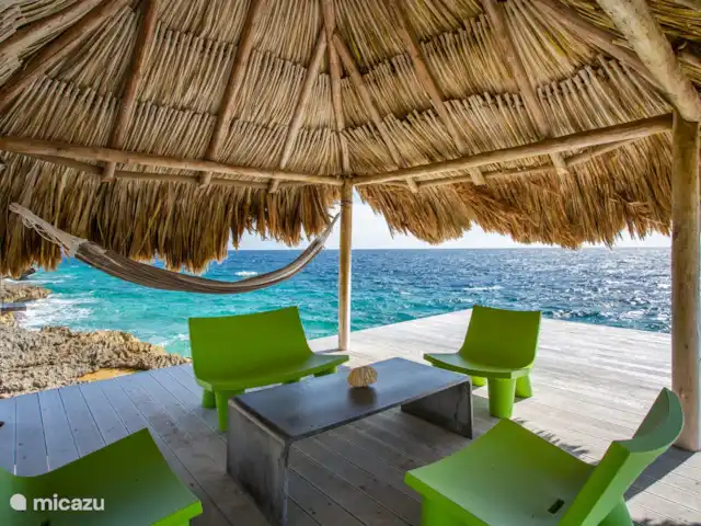 Villa frente al mar en el resort Boca Gentil en Curazao, Banda Arriba (este), Jan Thiel - villa Debajo de la gran palapa con asientos y las escaleras al mar.