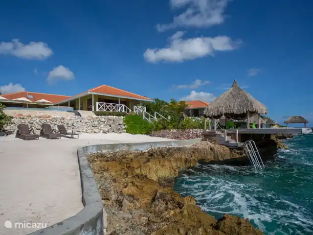 Villa frente al mar en el resort Boca Gentil en Curazao, Banda Arriba (este), Jan Thiel - villa La villa con vistas desde la gran terraza de la piscina. Ves la palapa con la terraza flotante en el mar.