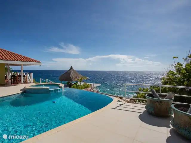Villa frente al mar en el resort Boca Gentil en Curazao, Banda Arriba (este), Jan Thiel - villa La villa con vistas desde la gran terraza de la piscina. Ves la palapa con la terraza flotante en el mar.