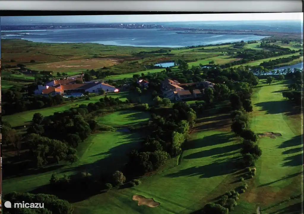 Luftbild der Residenz (Gebäude rechts) eingebettet in das Grün des Golfplatzes. Im Hintergrund das Meer und das Naturschutzgebiet mit Flamingos.