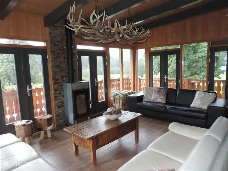 El jardín de invierno visto desde la esquina izquierda con vista a la estufa de leña y al sofá de cuero de 4 plazas.