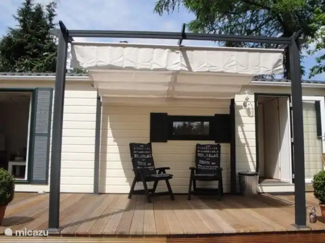 Sunny Chalet Beekbergen Veluwe huren in Nederland, Gelderland, Beekbergen - chalet Eén van de gezellige zitplekken met gelegenheid tot overkapping bij volle zon.
Er staat ook een eettafel met 4 stoelen op de veranda