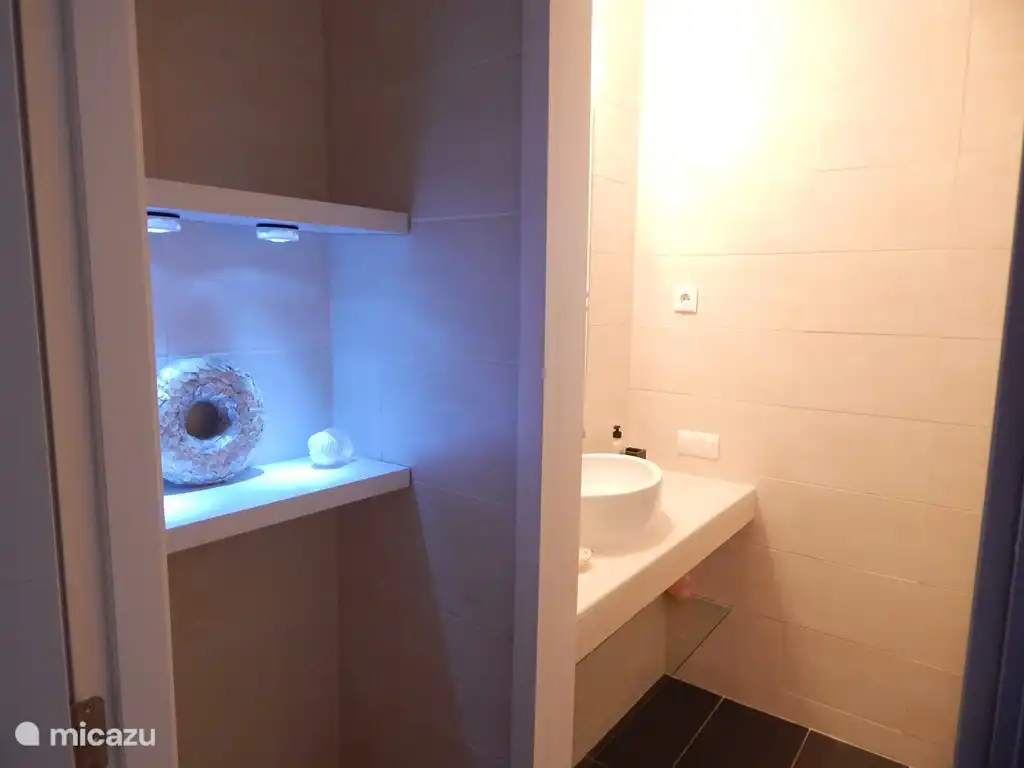 Beim Betreten von Bad 1 befindet sich gleich um die Ecke die komfortable ebenerdige Dusche und Toilette.