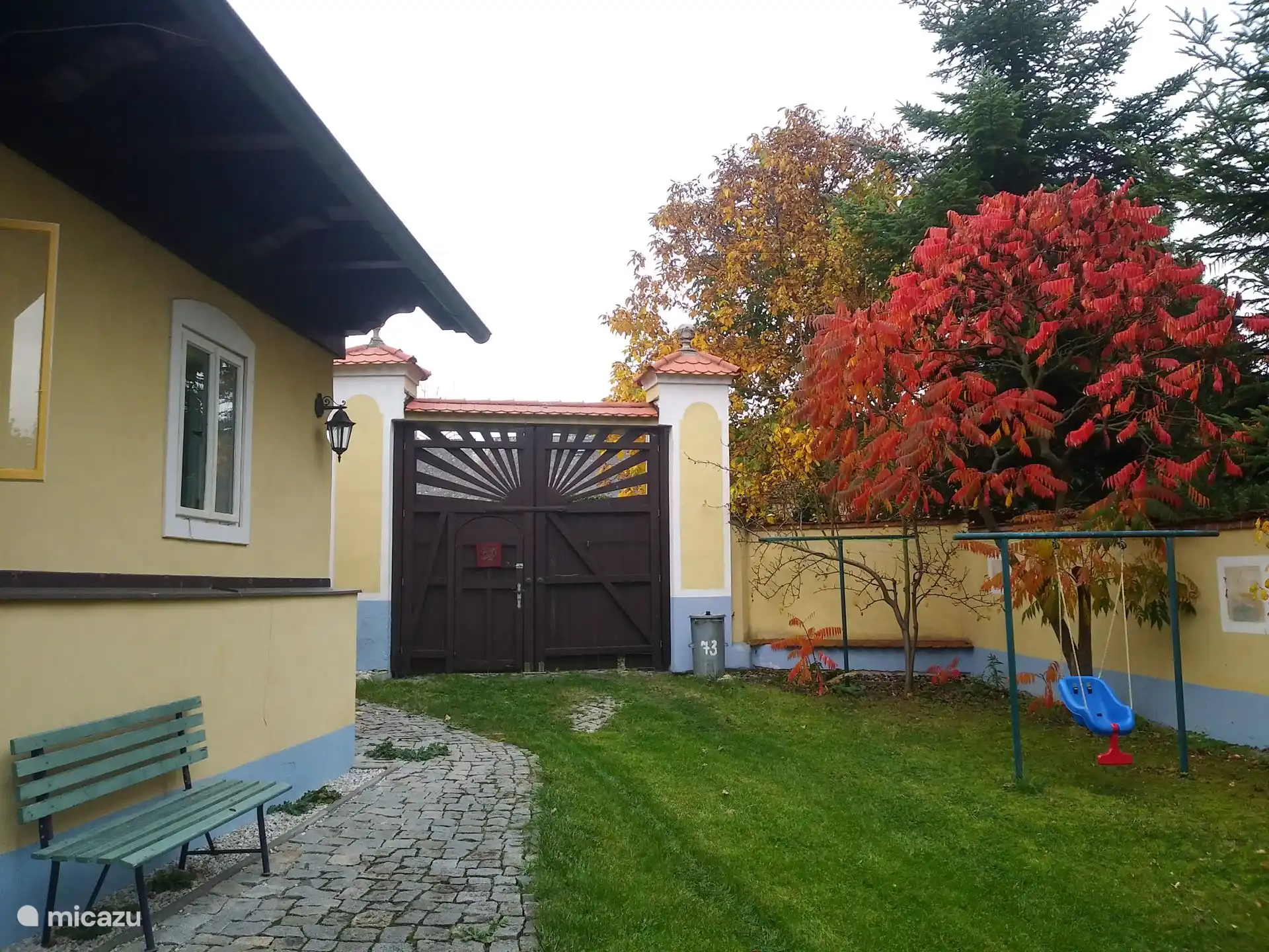 La parte delantera del patio del jardín con la puerta de entrada en otoño.