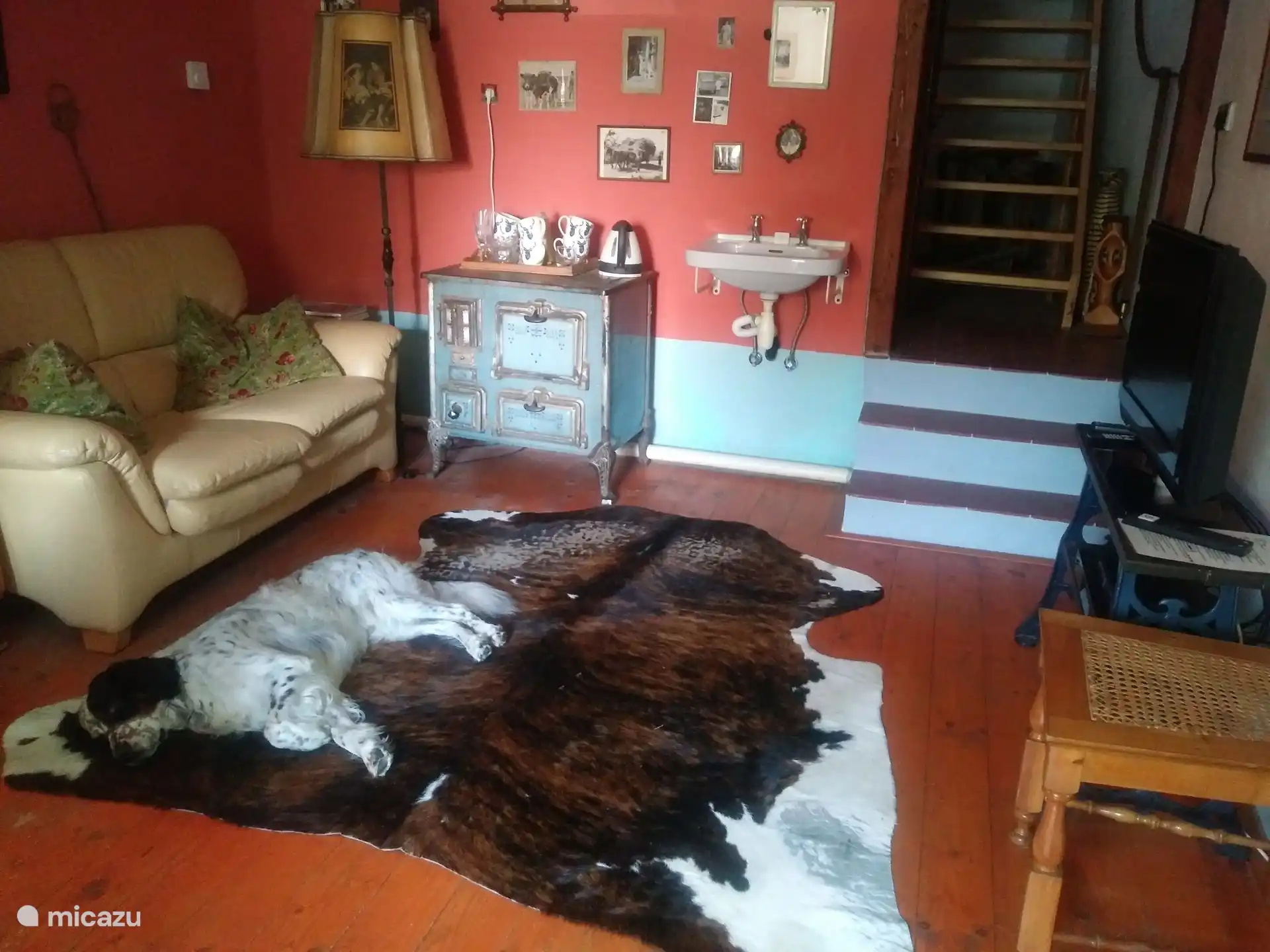 Salón con televisión, sofá y comedor con mesa y sillas.