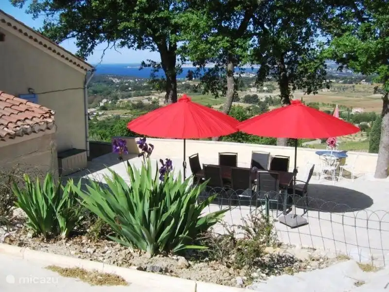 Von der Poolterrasse blickt auf die Grill-Terrasse, mit einem Hintergrund des Meeres.
