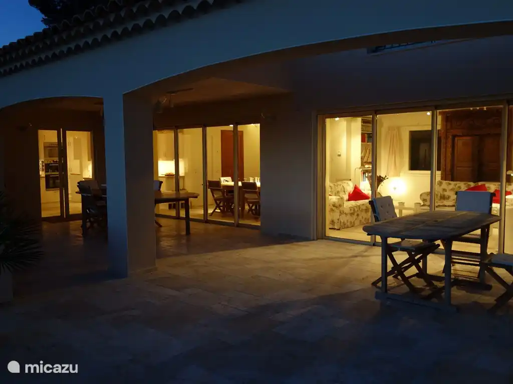 Die überdachte alte Terrasse am Abend. Rechts die zwei großen, 4 Meter breiten Schiebetüren zum Séjour. Diese Schiebetüren können sich vollständig öffnen (sie verschwinden in der Wand). Links die Schiebetüren zur Küche - die auch in der Wand verschwinden.