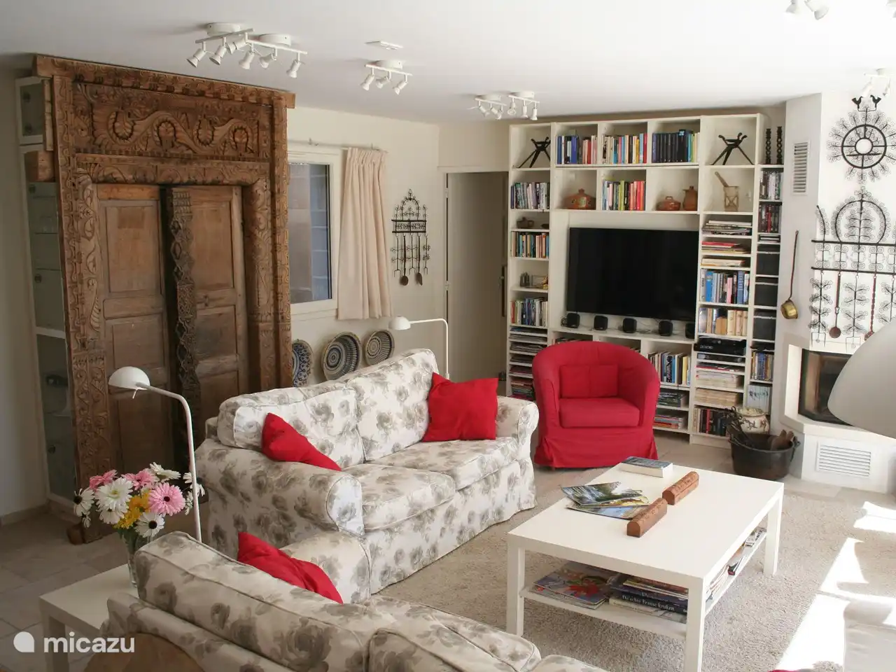 Een ruime familie woonkamer, met TV, veel boeken, veel DVDs en open haard