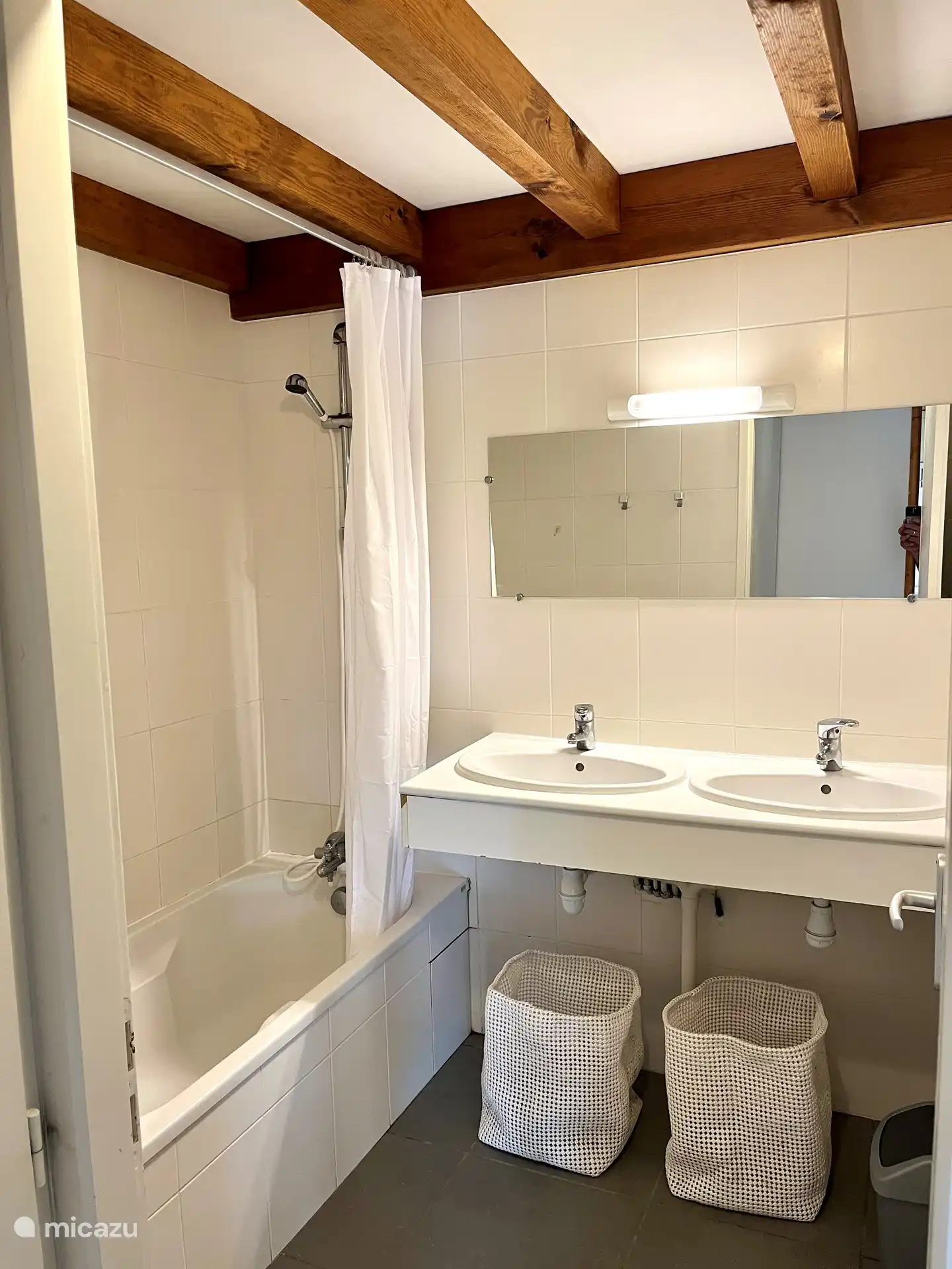 Badezimmer mit Badewanne und Doppelwaschbecken.