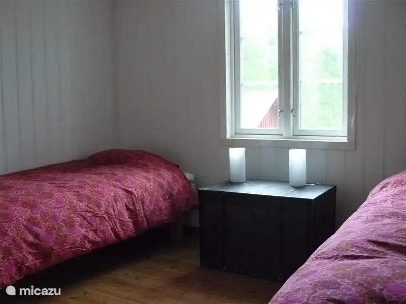 Schlafzimmer mit zwei Einzelbetten. Mit einem hölzernen Wandtafeln. Der Holzfußboden ist gemalt.