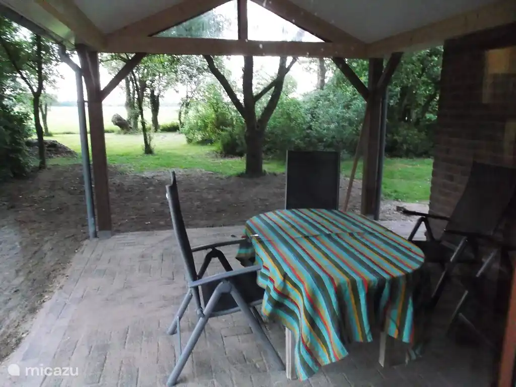 Auf der neuen überdachten Terrasse können Sie draußen essen mit Blick auf den Garten mit dem Goudreinet-Obstbaum und die Wiese mit den Kühen und Kopfweiden