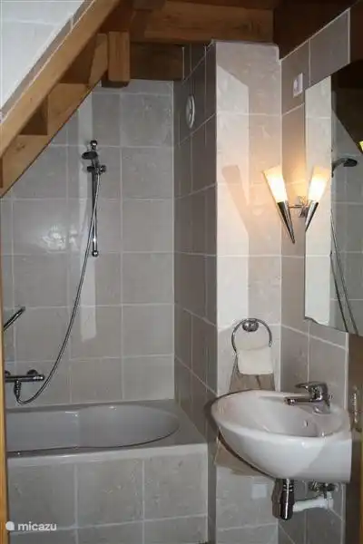 In de badkamer is een bad, douche en wastafel aanwezig. 