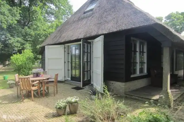 Via de openslaande deuren komt u uit op het terras. De voordeur is onder de veranda, waar tevens een bank staat om lekker te zitten