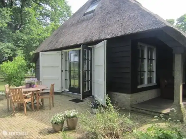 Dwarsgracht 39 en Países Bajos, Overijssel, Giethoorn - casa de campo A través de las puertas francesas se sale a la terraza. La puerta principal está debajo de la terraza, donde también hay un sofá para sentarse cómodamente.