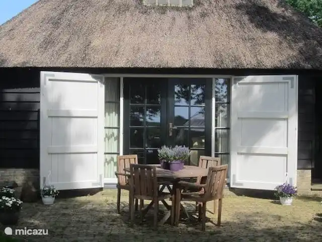 Dwarsgracht 39 en Países Bajos, Overijssel, Giethoorn - casa de campo vista desde el jardín de la casa de vacaciones y terraza. Se proporcionan mesa y sillas.