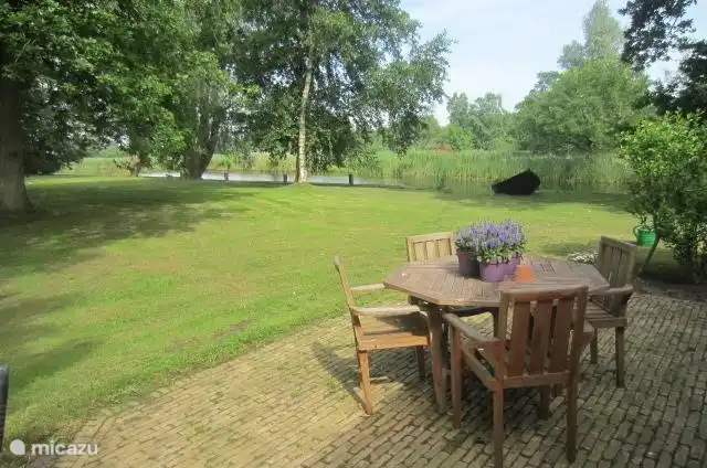 Uitzicht vanaf het terras op de tuin, de voorbij varende boten en het nationale park