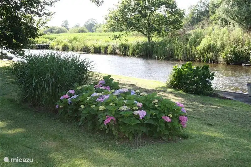 Uitzicht vanuit de keuken en woonkamer naar de tuin, gracht en  het Nationaal Park de Weerribben-Wieden. Vanuit de tuin stapt u zo uw (gehuurde) bootje in om te genieten van het water en kunt u Giethoorn en omgeving bezoeken. Tevens kunt u heerlijk fietsen en wandelen en zijn er kano's te huur