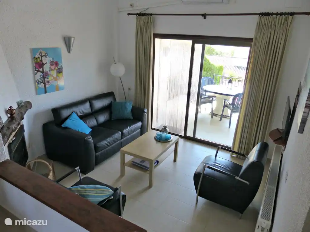 Gemütliches Wohnzimmer mit Essecke und Sitzecke und Zugang zur überdachten Terrasse über Schiebetüren