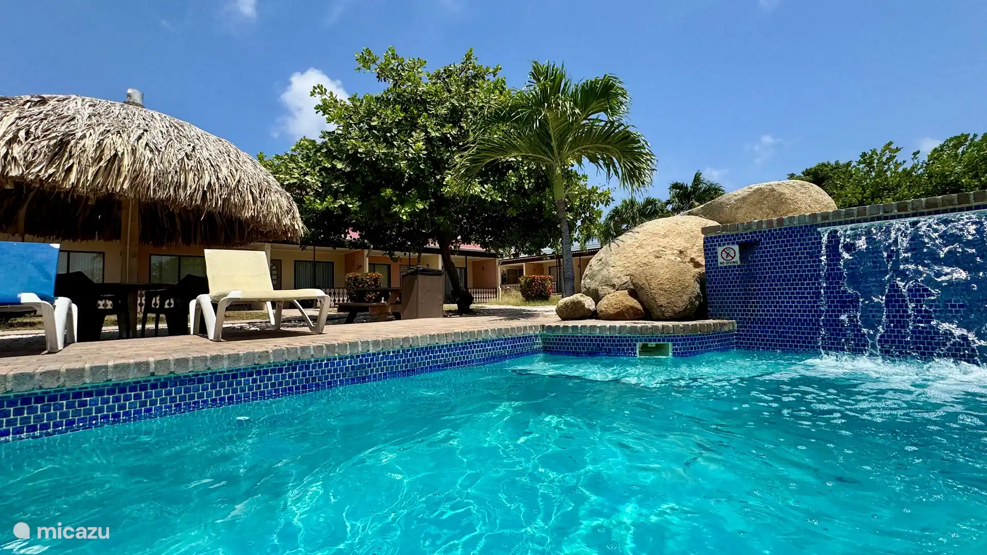 Viele bequeme Sitzgelegenheiten im Schatten und Sonnenliegen am Pool.