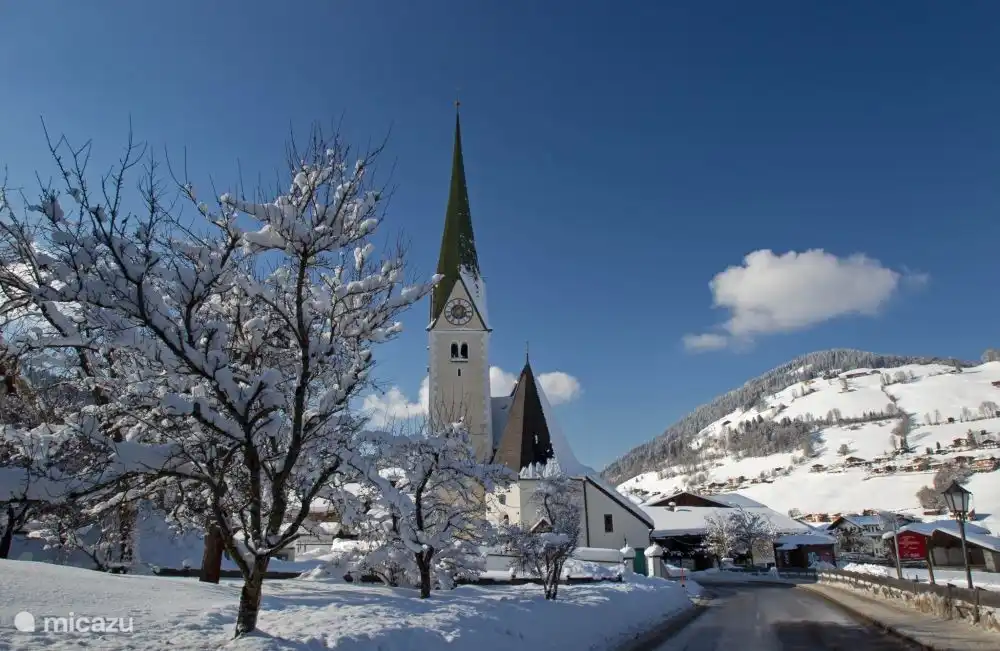 The main street of Niederau, with the characteristic church in a beautiful winter landscape.