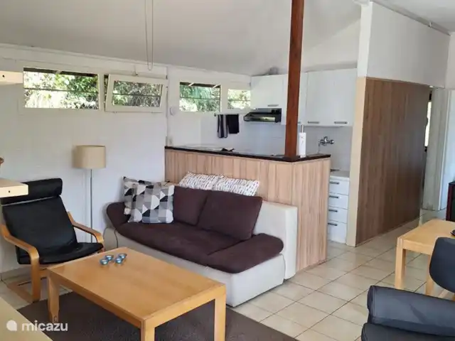 Sunclass Bungalow C28 huren in Italië, Gardameer, Tignale - vakantiehuis Het aanzicht van een deel van de woonkamer, de open keuken en de gang naar de slaapkamers en de badkamer. De woonkamer heeft een televisie met video-speler, een dvd-speler, boeken, films en bordspellen.