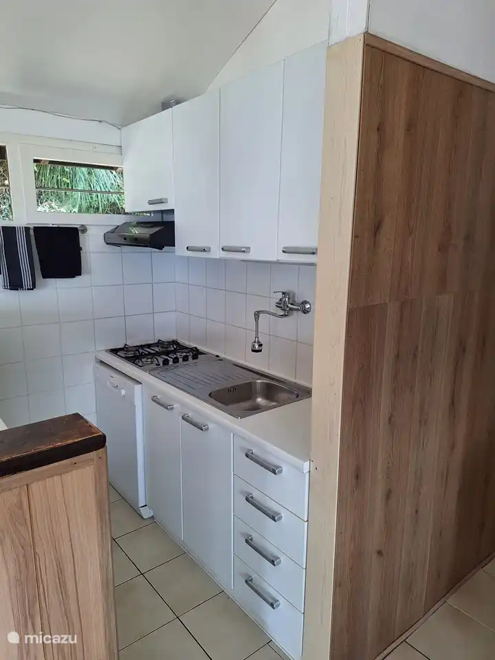 La cocina con todo lo necesario, como una combinación de nevera/congelador, una estufa de gas de cuatro quemadores y un lavavajillas.