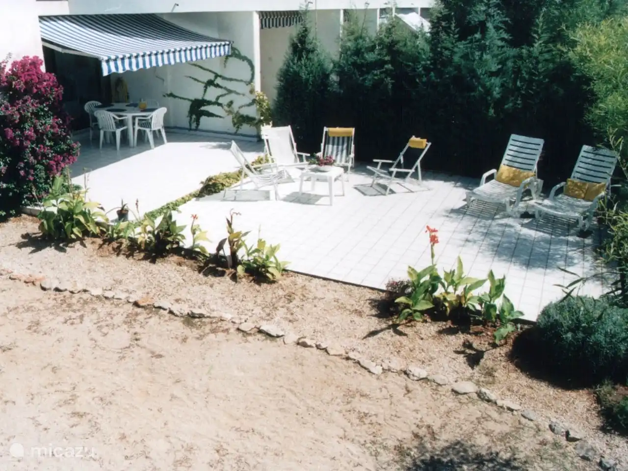 Die überdachte Terrasse (mit Tisch) und die große Terrasse