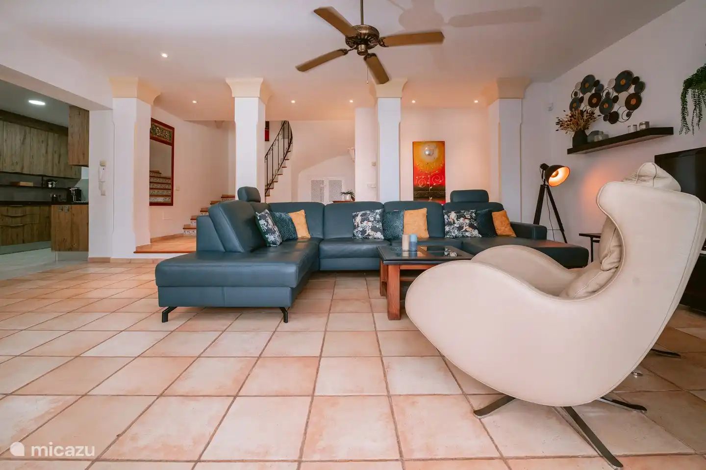 Wohnzimmer mit gemütlicher Sitzecke am Kamin, Flachbildfernseher, Deckenventilator und Schiebetüren zur teilweise überdachten Terrasse