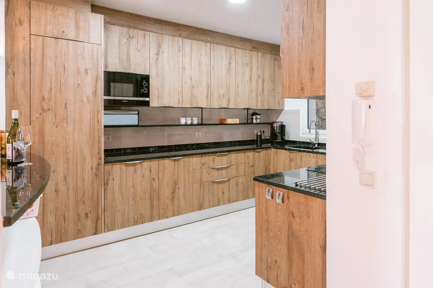 Die halboffene, voll ausgestattete Küche mit Geschirrspüler, Mikrowelle, Backofen, Kaffeemaschine und Kühl-/Gefrierschrank.