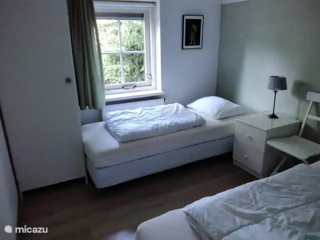 Veluwerijck 8 en Países Bajos, Güeldres, Ermelo - casa de campo Dormitorio más pequeño con 2 camas somier de 80x200 cm, 2 almohadas, 2 edredones de 140x200 cm, silla, mesita de noche, lámpara de noche, armario y suelo laminado.