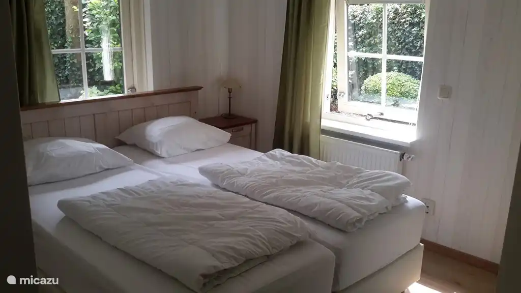 Grande chambre avec 2 sommiers neufs 2x80x200 cm avec 2 couettes 140x200 cm et 2 oreillers, 2 chevets avec lampes de chevet, radio-réveil, grande armoire, chaise et stratifié au sol