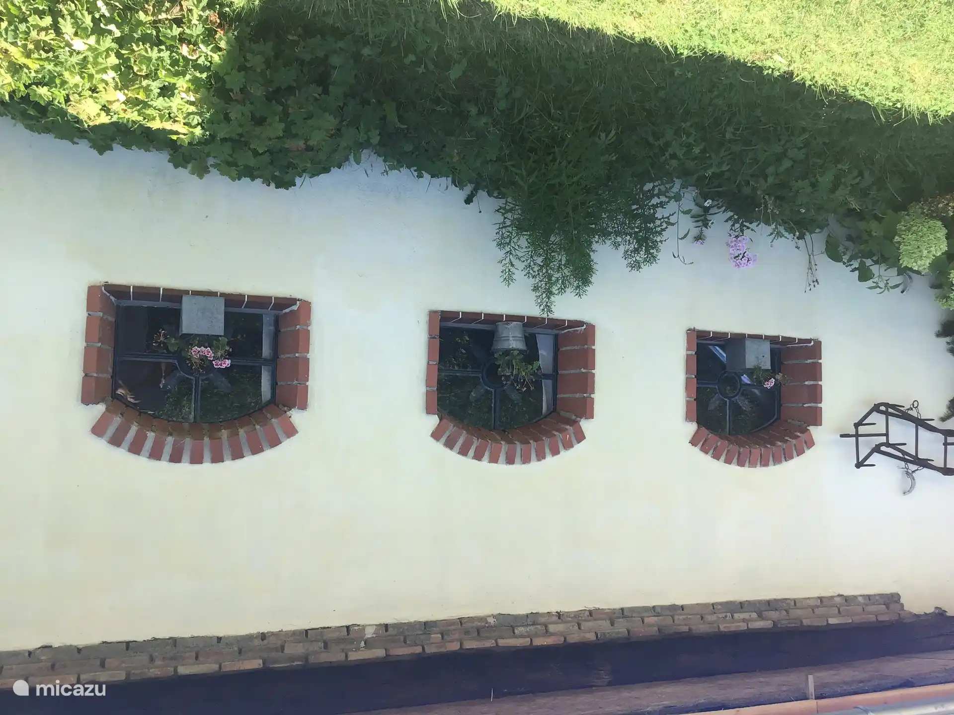 Die Seite der Gîte mit den drei Fenstern und den Blumen.