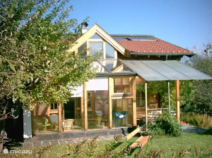 Blick vom Garten auf den Wintergarten. Rechts der überdachte Bereich, wo man bei Regen draußen sitzen kann.