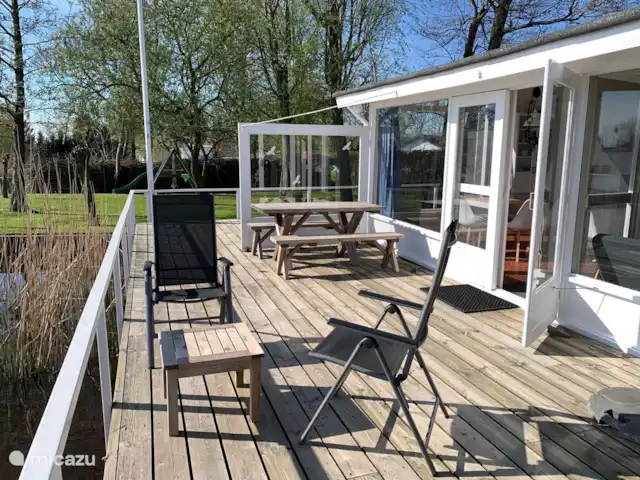 vakantiehuis huren in Nederland, Friesland, Grouw – Heerlijk vakantiehuis aan het water Heerlijk terras aan het water op het zuiden. Voorzien van aparte bank, 6 tuinstoelen, parasol en eettafel met 2 zitbanken