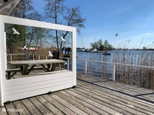 vakantiehuis huren in Nederland, Friesland, Grouw – Heerlijk vakantiehuis aan het water Heerlijk terras aan het water op het zuiden. Voorzien van aparte bank, 6 tuinstoelen, parasol en eettafel met 2 zitbanken