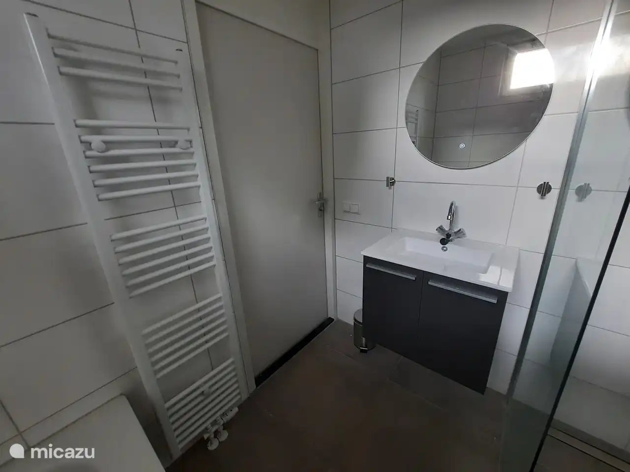 Das Badezimmer im Erdgeschoss verfügt über ein geräumiges Waschbecken, eine Badewanne und eine ebenerdige Dusche.