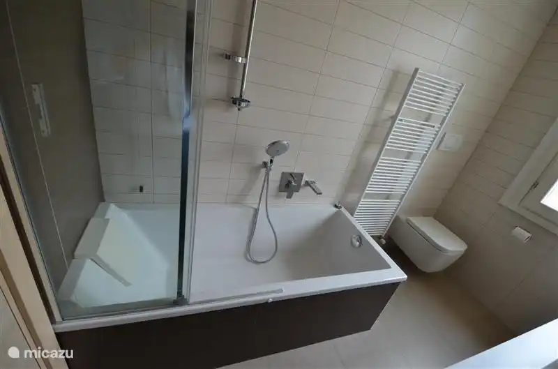 Das Badezimmer verfügt über eine Badewanne und eine Dusche mit Echtglasschiebewand.