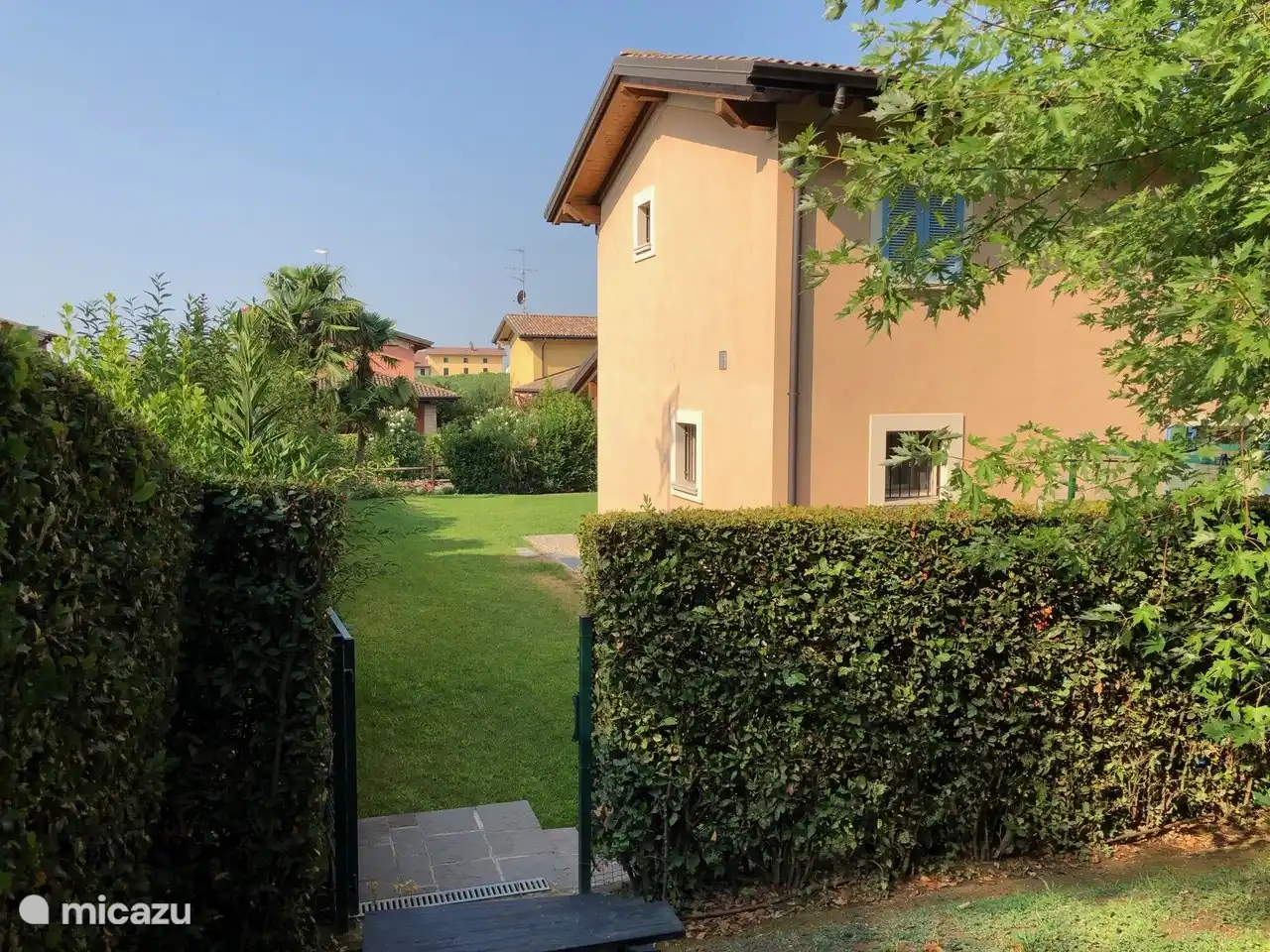 Vom Hinterhof durch das Tor zum Garten mit Pool.