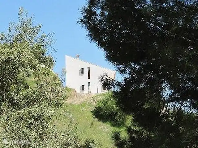 Villa de vacances de luxe, Finca Nirvana | Espagne, Andalousie, Colmenar - maison de vacances La Finca vue de la vallée. Le côté ouest de la maison a des blocs de construction colorés qui donnent une belle lumière colorée dans le hall de la maison. Vous marchez directement dans les grands espaces où poussent de nombreux amandiers et oliviers. Ici et là, vous trouverez également des orangers, des citronniers et des tilleuls.