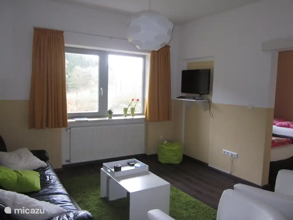 Das Wohnzimmer, mit einem angrenzenden Schlafzimmer. Zeitschriften, Bücher, DVDs und Spiele sind vorhanden