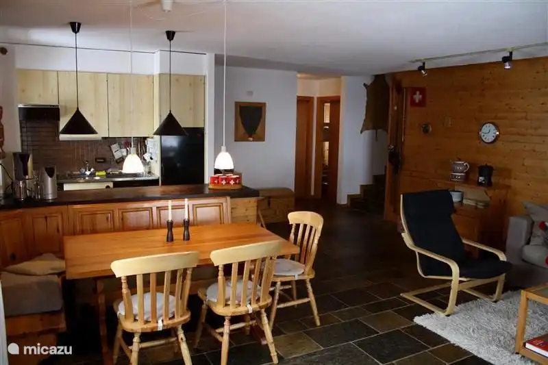 De eettafel en daar achter de open keuken. Achter in de kamer zie je de toegang tot 1 van de slaapkamers (rechts)