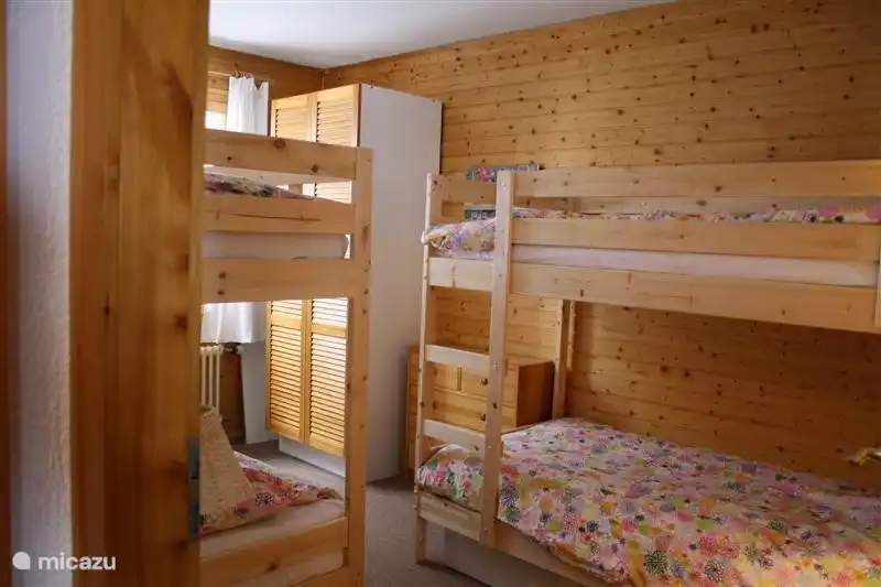 De 2e slaapkamer bij binnenkomst gefotografeerd. Te zien is een grote kledingkast rechts achterin . Onder de bedden bevinden zich nog 2 opberglades.