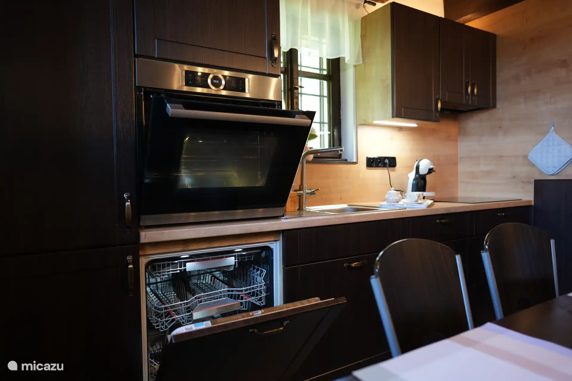 Eine moderne, gut ausgestattete Küche mit einer kombinierten Mikrowelle/Backofen, einem Geschirrspüler, einer Dolce-Gusto-Kaffeemaschine, einem Quooker zum Kochen von Wasser aus dem Wasserhahn und einem Induktionskochfeld