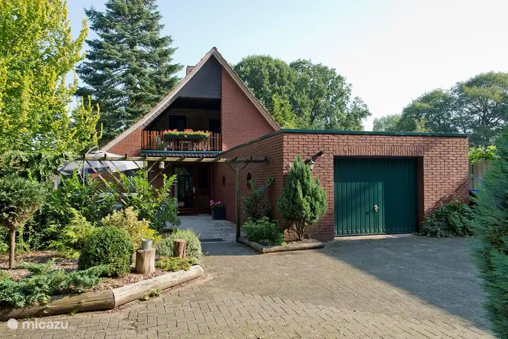 Die vorderseite vom Haus mit Blick auf die Garage, Scheune mit Stall und Hof. Oben können Sie den überdachten Balkon sehen. Neben der Garage ist eine große Terrasse, wo man schön sitzen kann.
