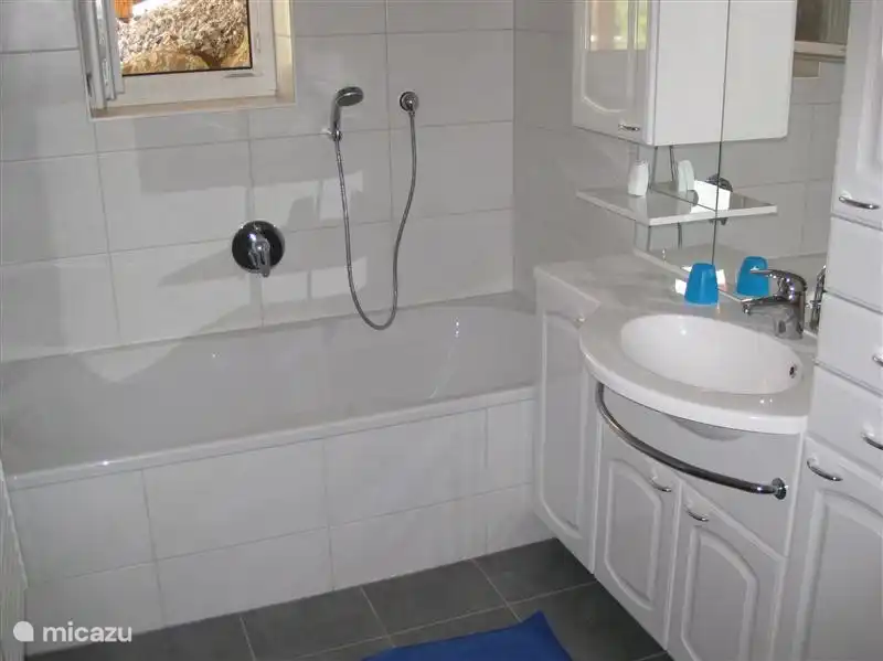 Baño en sótano con bañera, lavabo y cabina de ducha separada