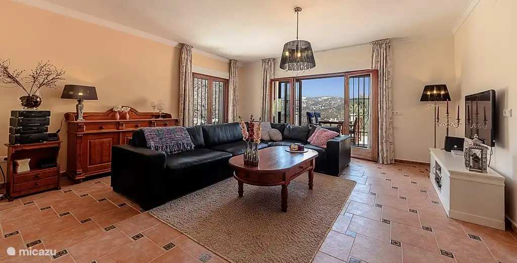 Wohnzimmer mit großem Ecksofa. Durch das Wohnzimmer auf die andere Terrasse ist im Sommer kühler als der Terrasse am Pool.