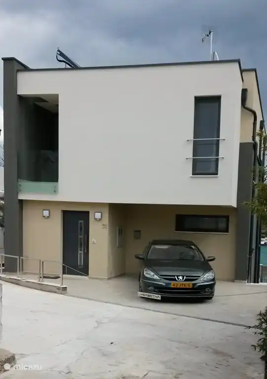 Die Vorderseite des Hauses mit dem Eingang und Parkplatz für zwei Autos. 