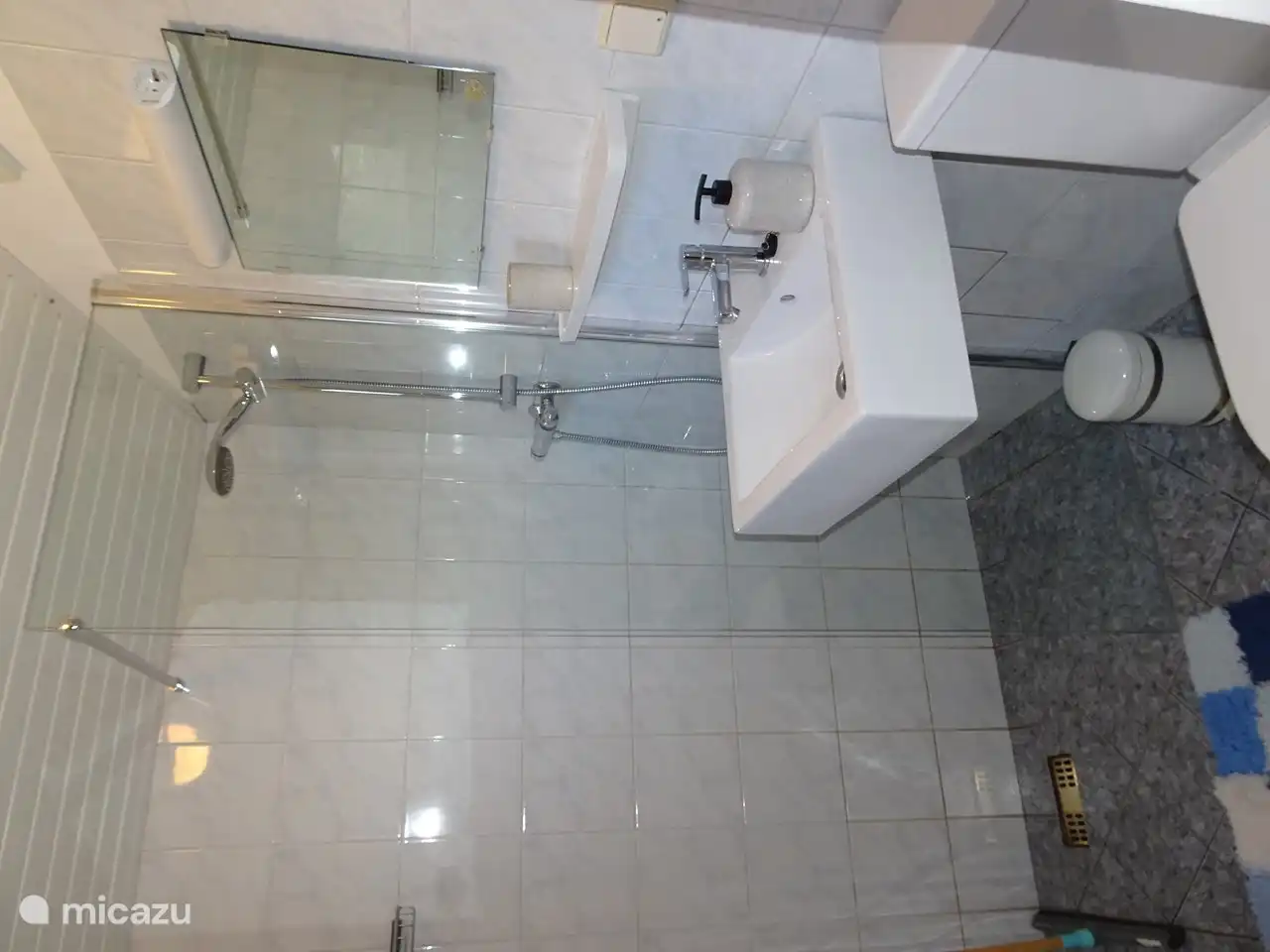 Nette toilet-doucheruimte met verhoogd toilet, wastafel  en glazen douchewand. Voorzien met schoon douchematje.