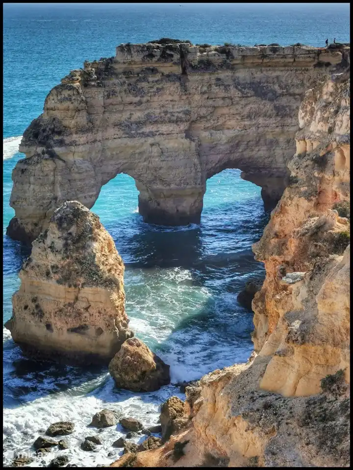 Felsformation vor Praia Marinha, Boote fahren unter den Bögen hindurch.