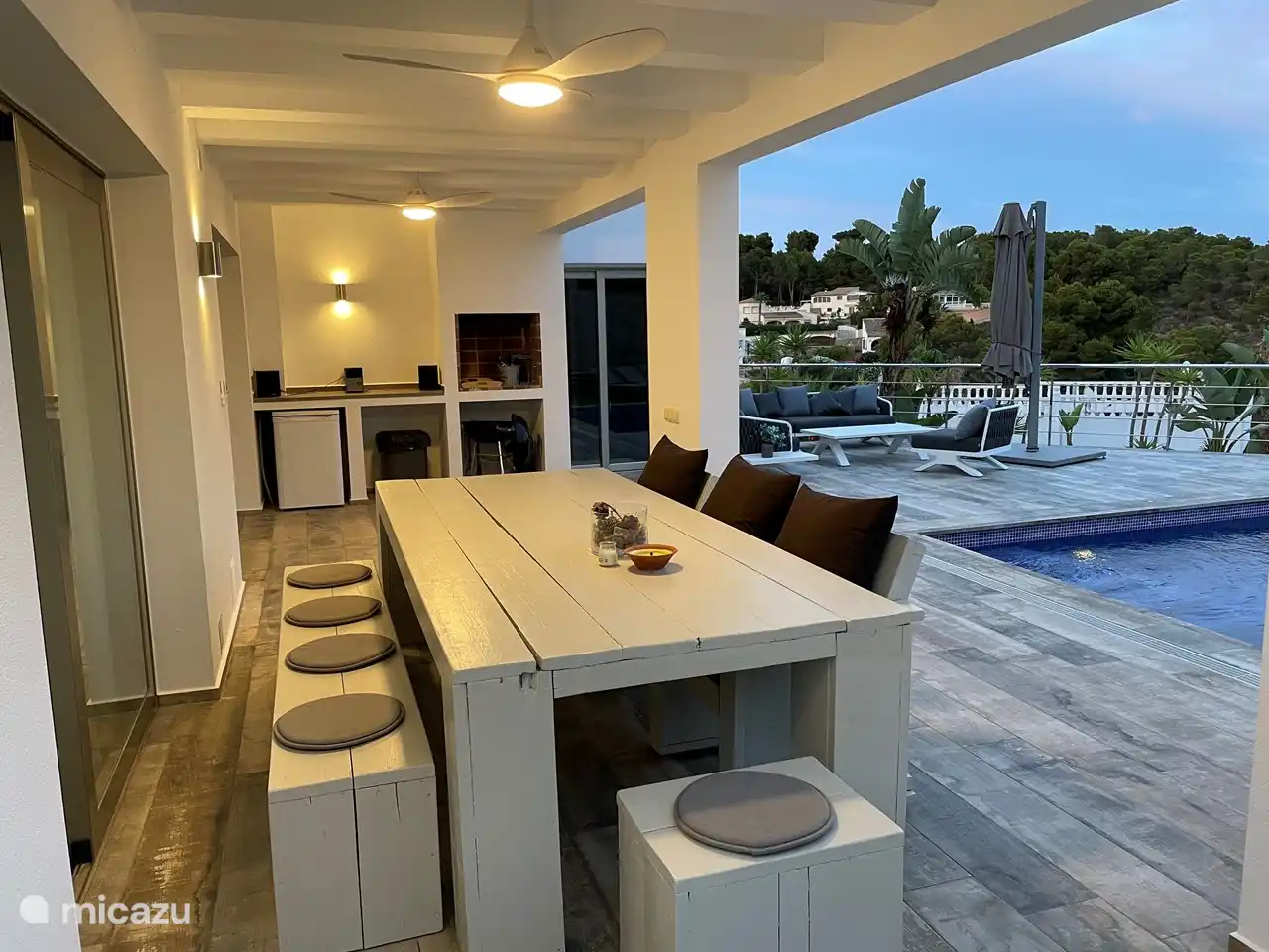 Großer Esstisch unter dem Baldachin mit Ventilatoren und Beleuchtung.